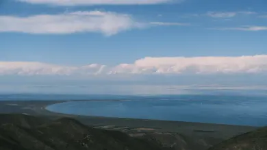 青海湖，蓝色湖水延伸到远处山脉，天空铺着薄云